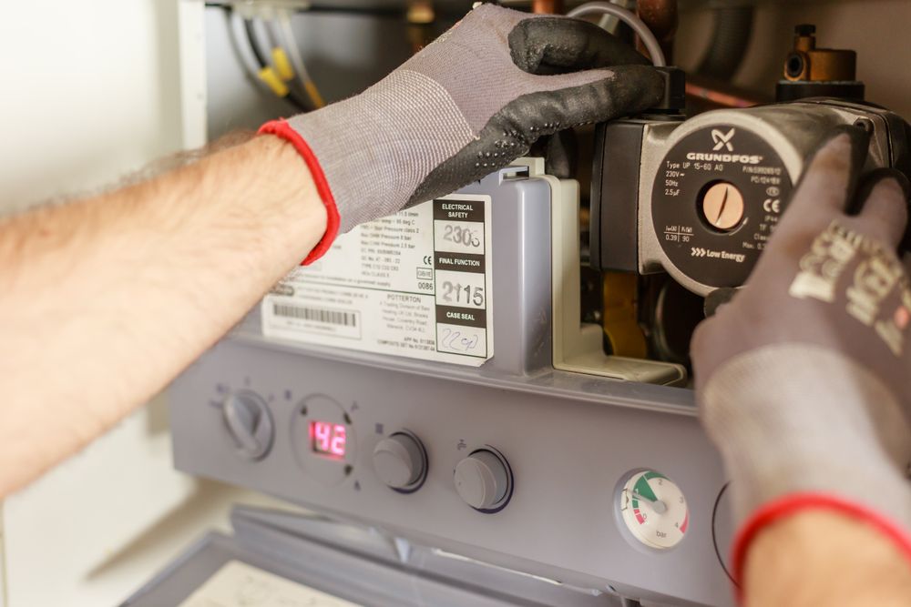 Mains gantées intervenant sur le circulateur d'une chaudière
